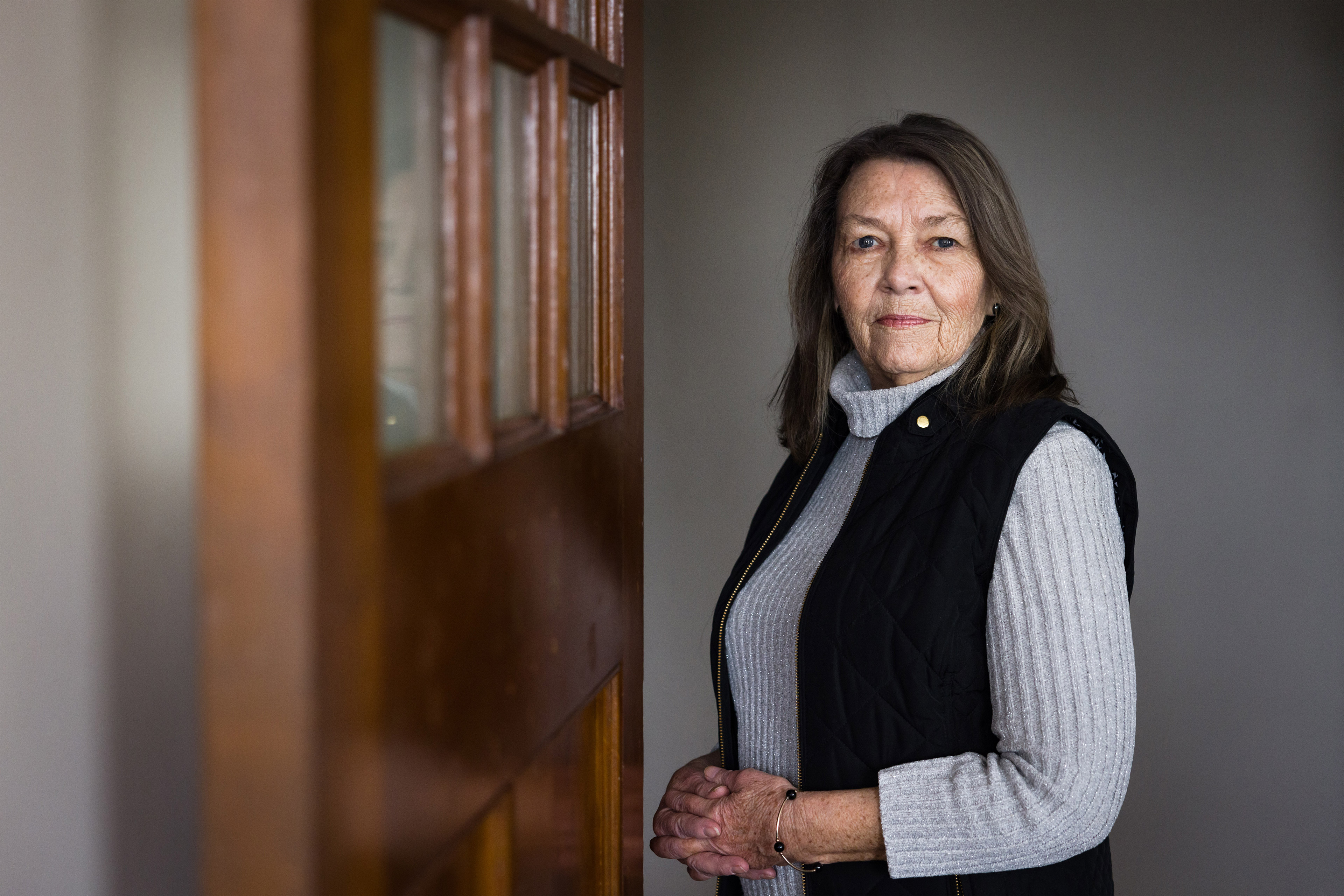 A woman stands by a bookshelf.