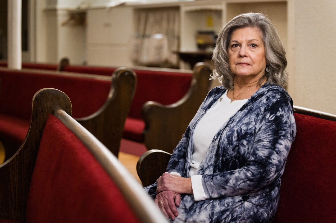 A woman sits in a church pew.