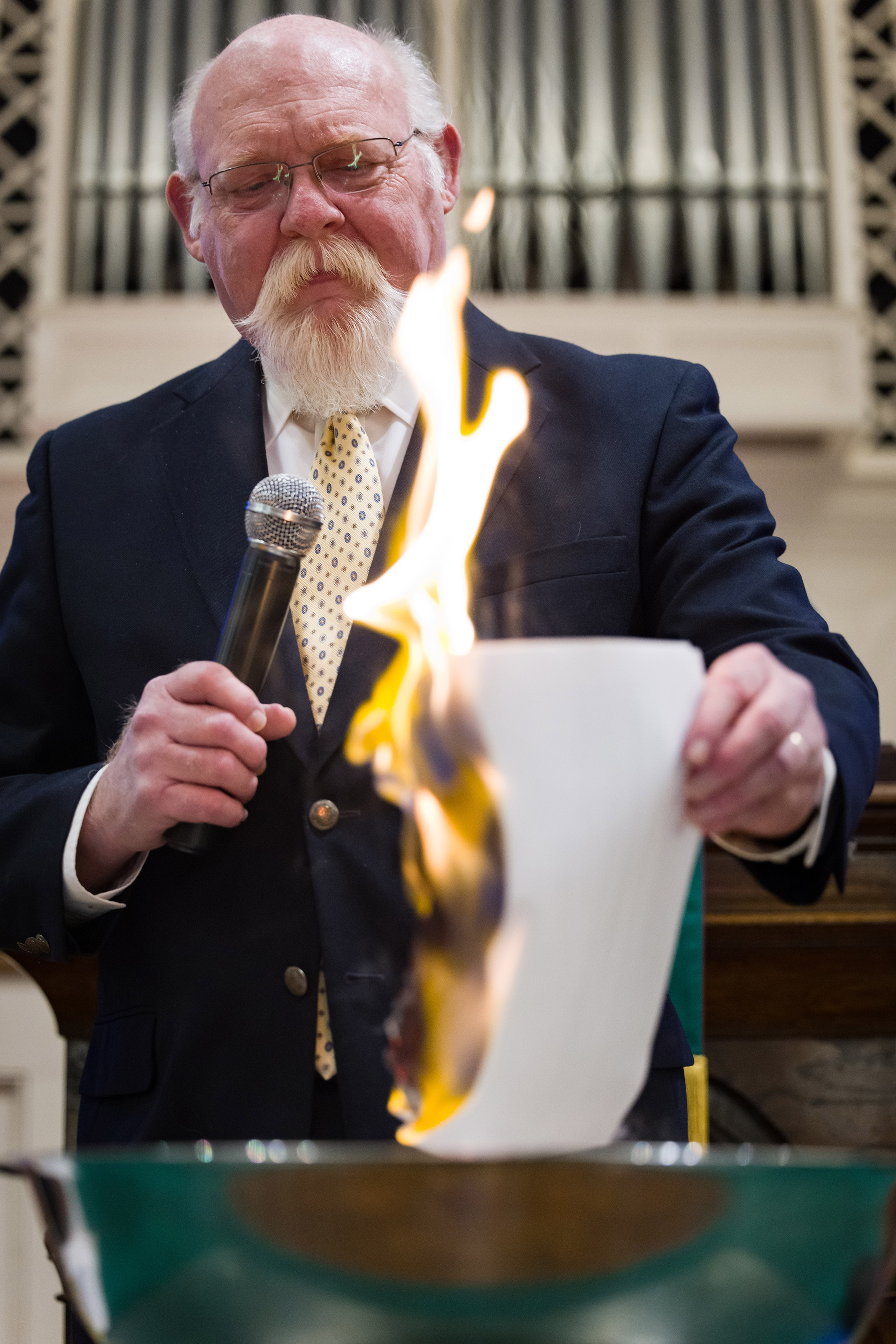 Rev. John Jackman burns a piece of paper.