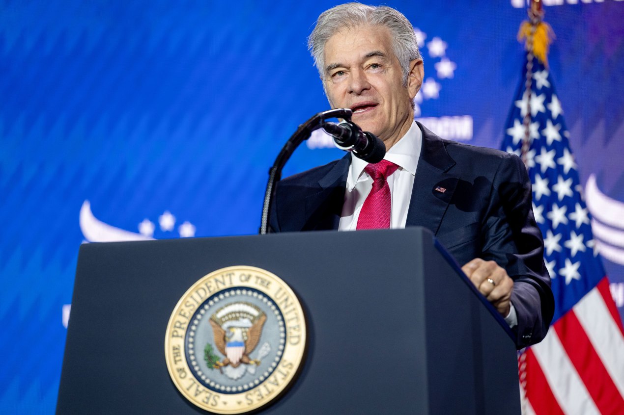 A man with white hair stands behind a lectern with the seal of the President of the United States on it, and speaks into a microphone.