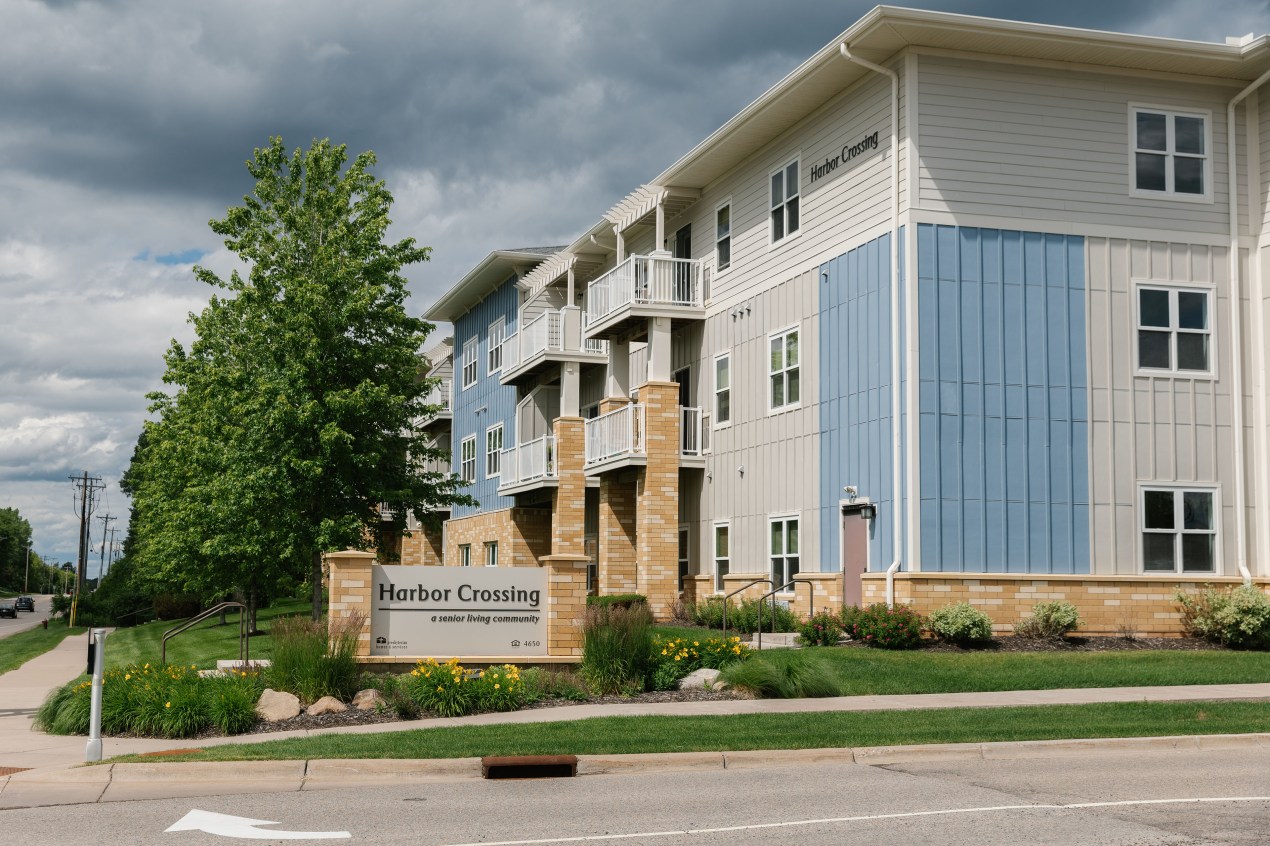An image of the exterior of a three-story building, with a sign that says "Harbor Crossing"