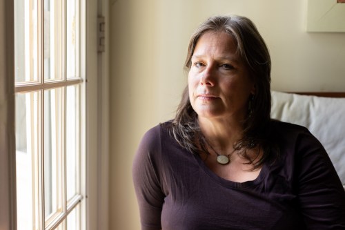 A woman poses for a portrait as she sits next to a window