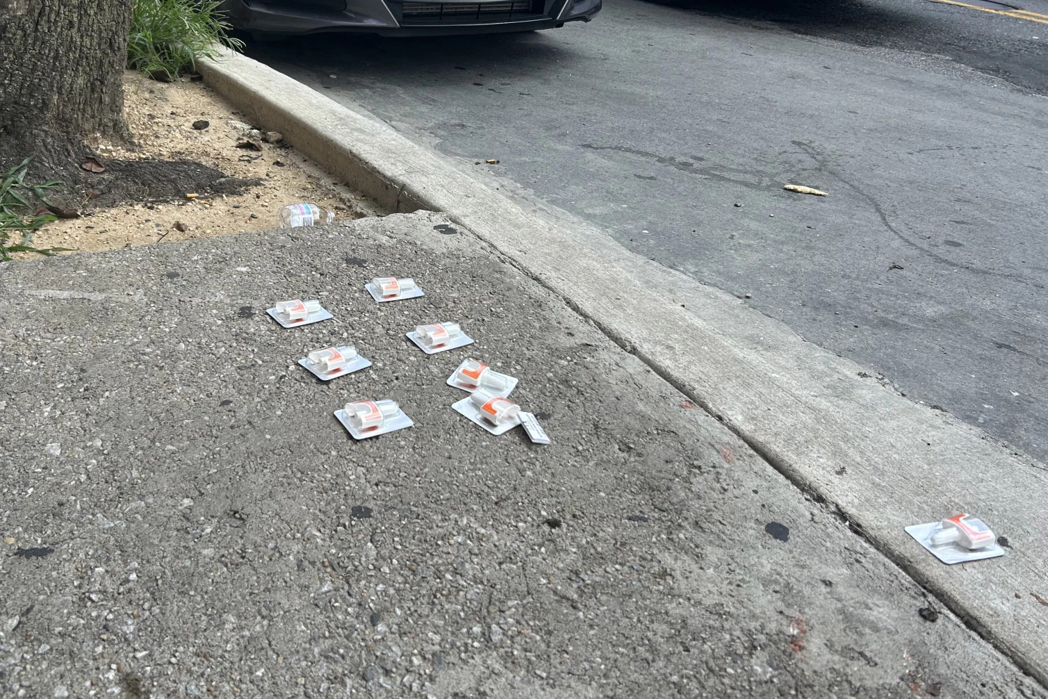 Eight packages of naloxone are left on a sidewalk.