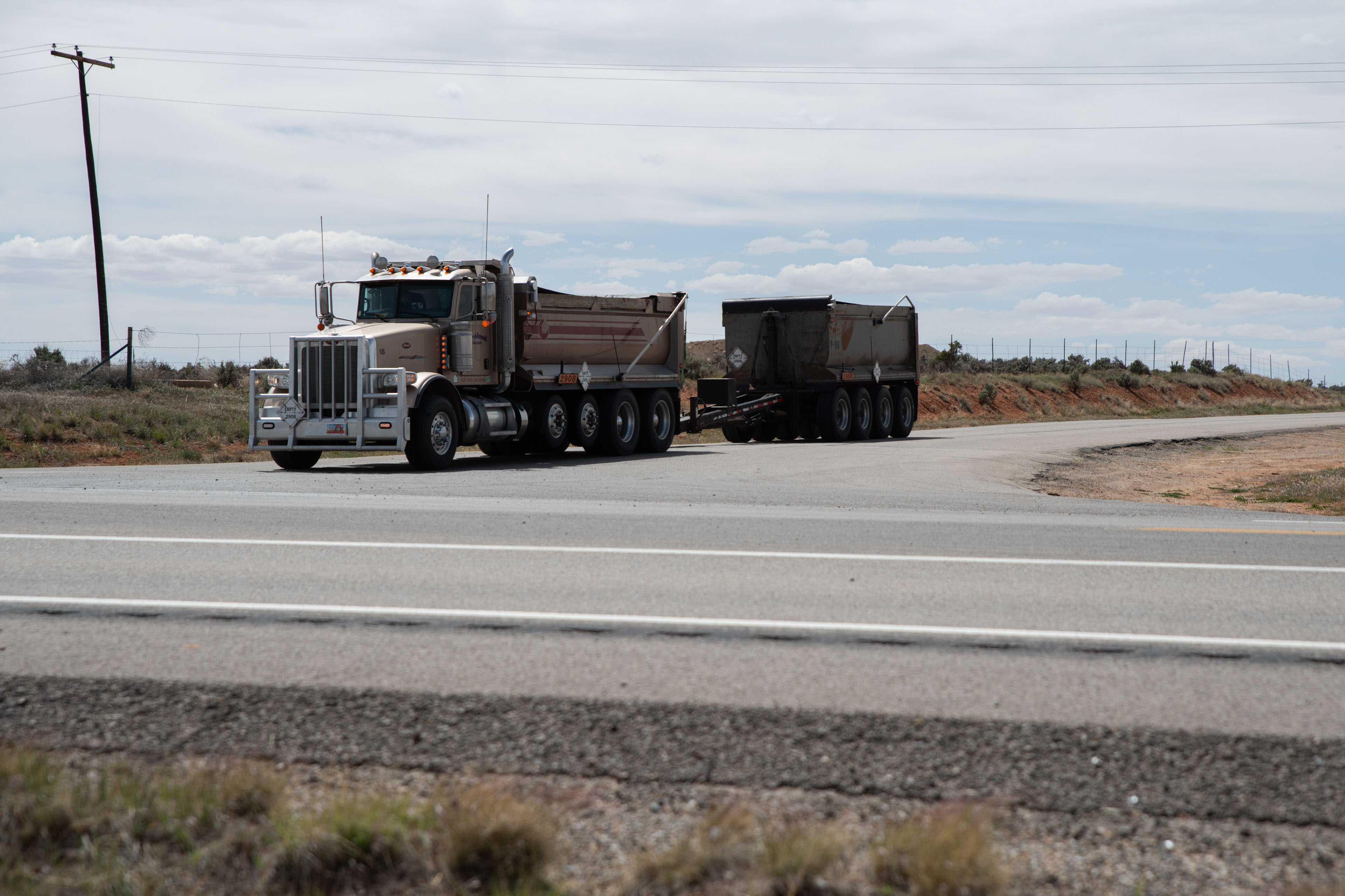 A photo of a 10-wheeler dump truck hauling a dump trailer behind it.