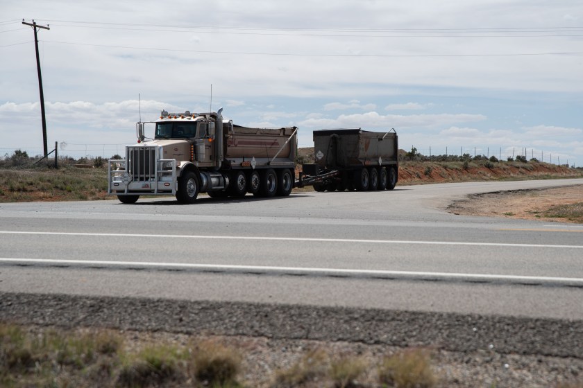 A photo of a 10-wheeler dump truck hauling a dump trailer behind it.