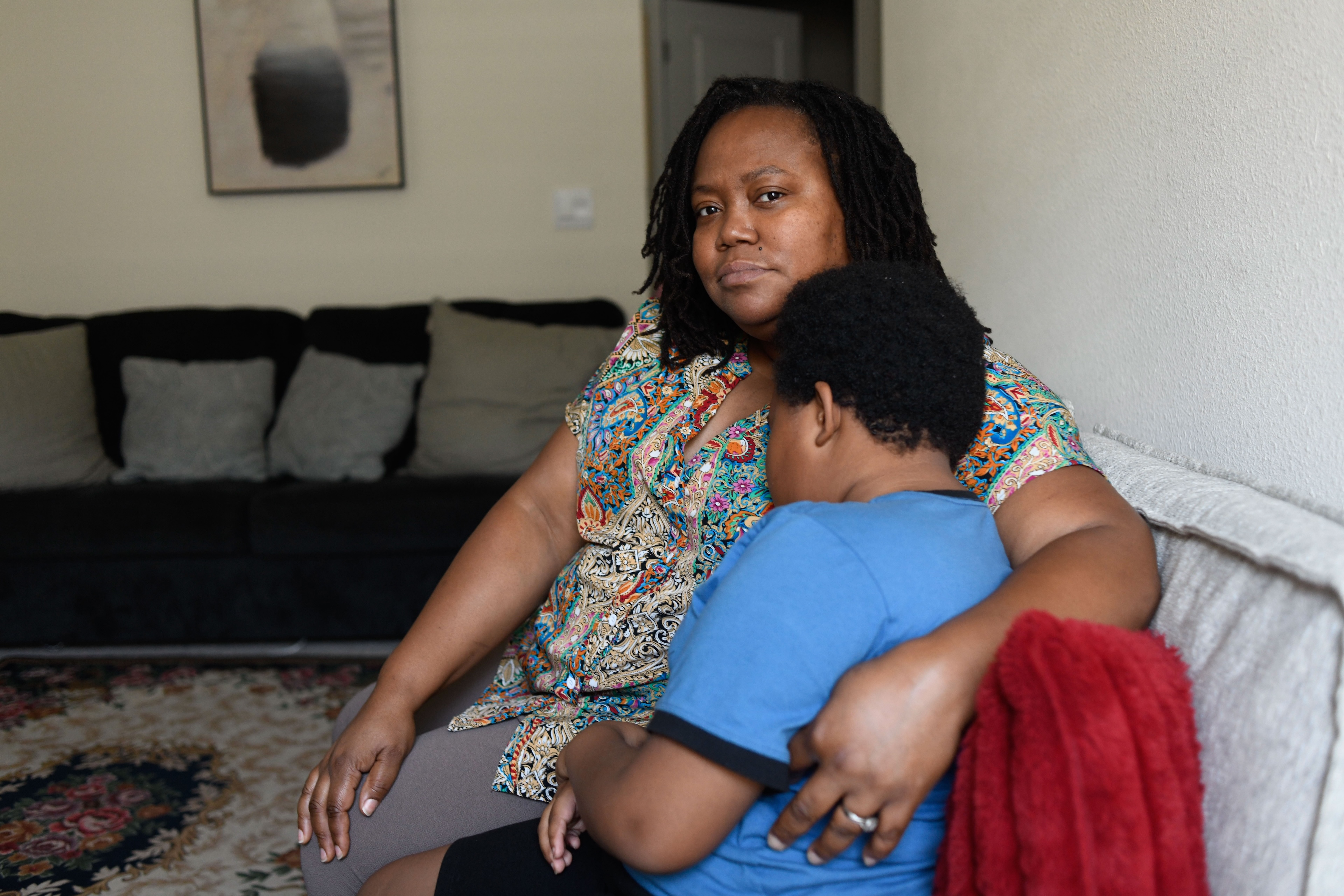 A woman sits on a couch embracing her young son