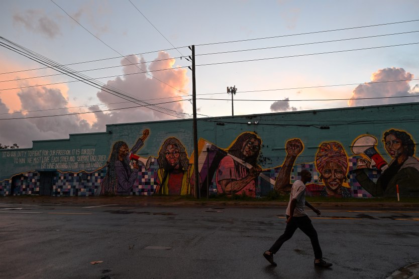A photo of a man walking past a mural on the side of a building in Jacksonville, Florida.