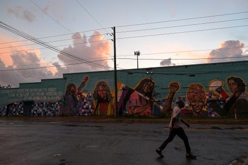 A photo of a man walking past a mural on the side of a building in Jacksonville, Florida.