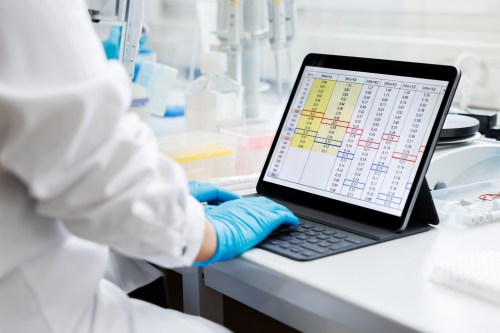 A photo of a clinical researcher in a laboratory working on a tablet.