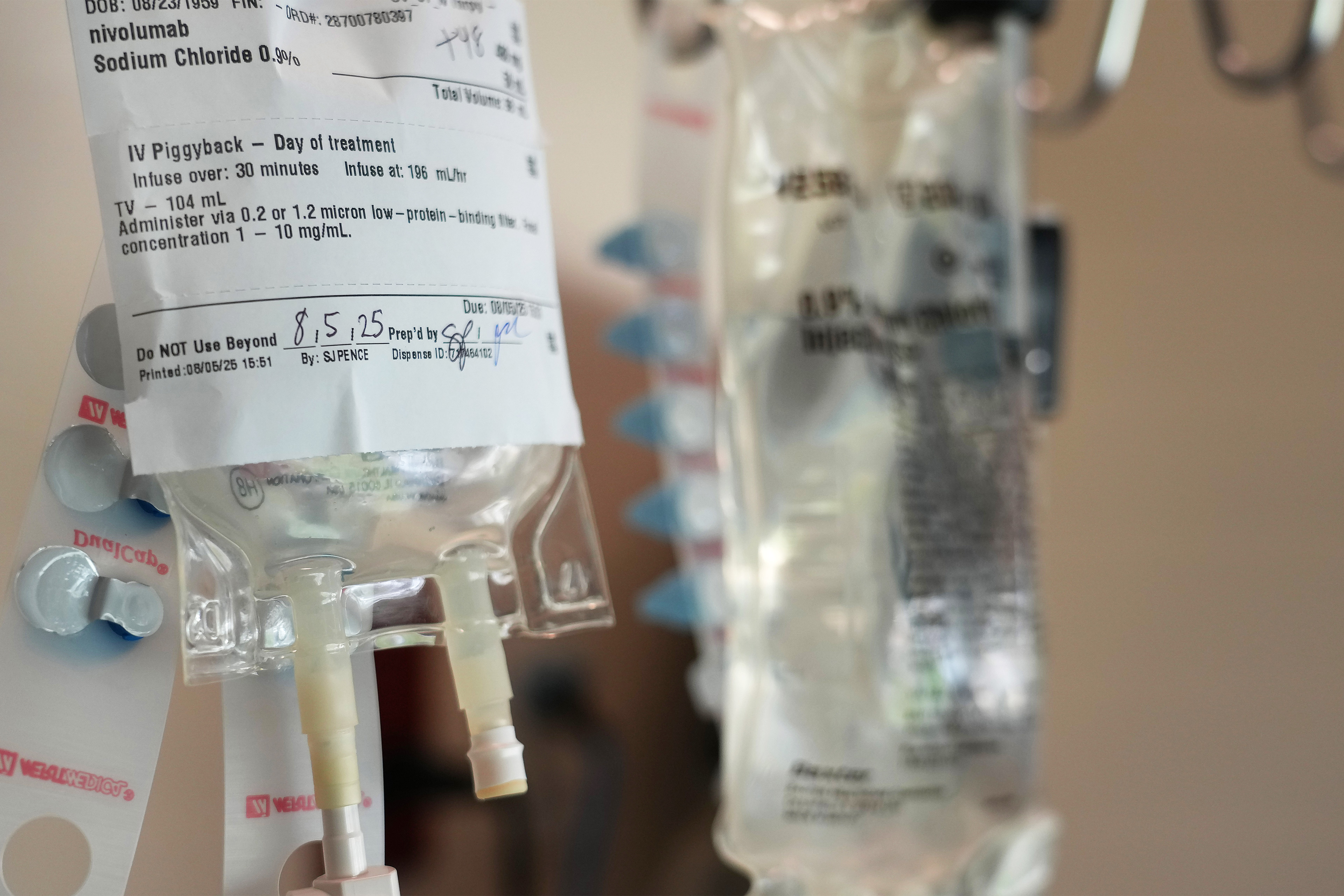 A photo of two IV bags as someone receives immunotherapy medication for melanoma treatment. The leftmost IV bag has "nivolumab" written on it.