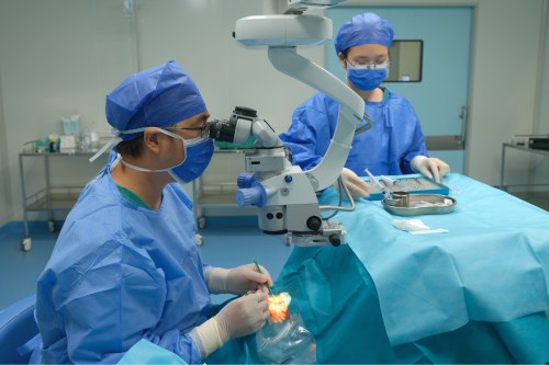 A photo of a doctor and a nurse in surgical garb working together to do cataract surgery.