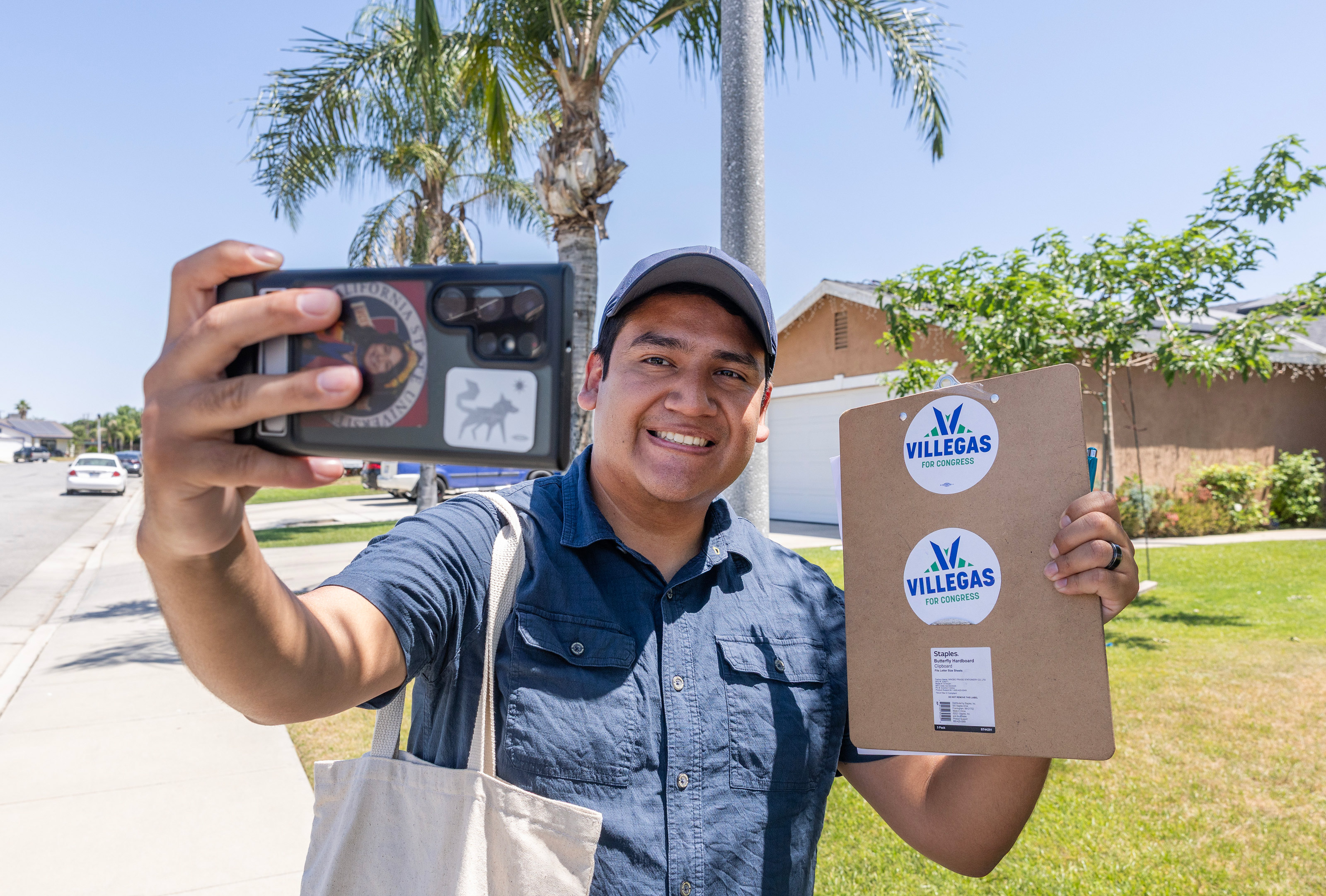 A photo of Randy Villegas taking a selfie while holding up campaign stickers.