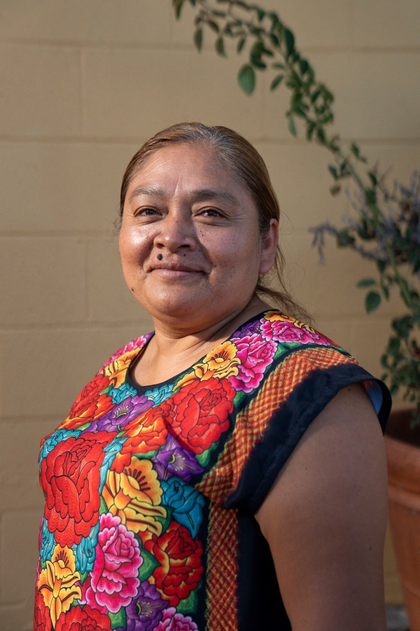 A portrait of a woman wearing a colorful embroidered short sleeve shirt.