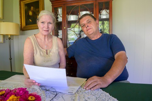 A photo of a couple seated at a table. Amye Joseph holds a piece of paper.