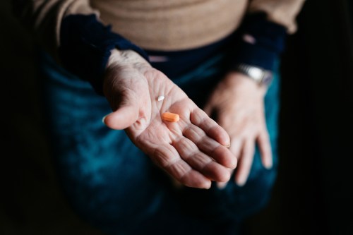 A close up of an elderly woman's hand showing a few pills.