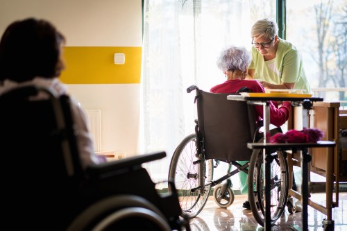 Nurse feeding old woman in wheelchair
