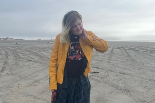 A photo of a young woman standing on a beach.