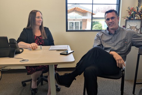 A woman and man sit indoors in an office.