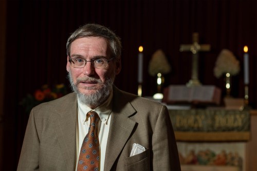 A man stands in front of an altar inside a church.