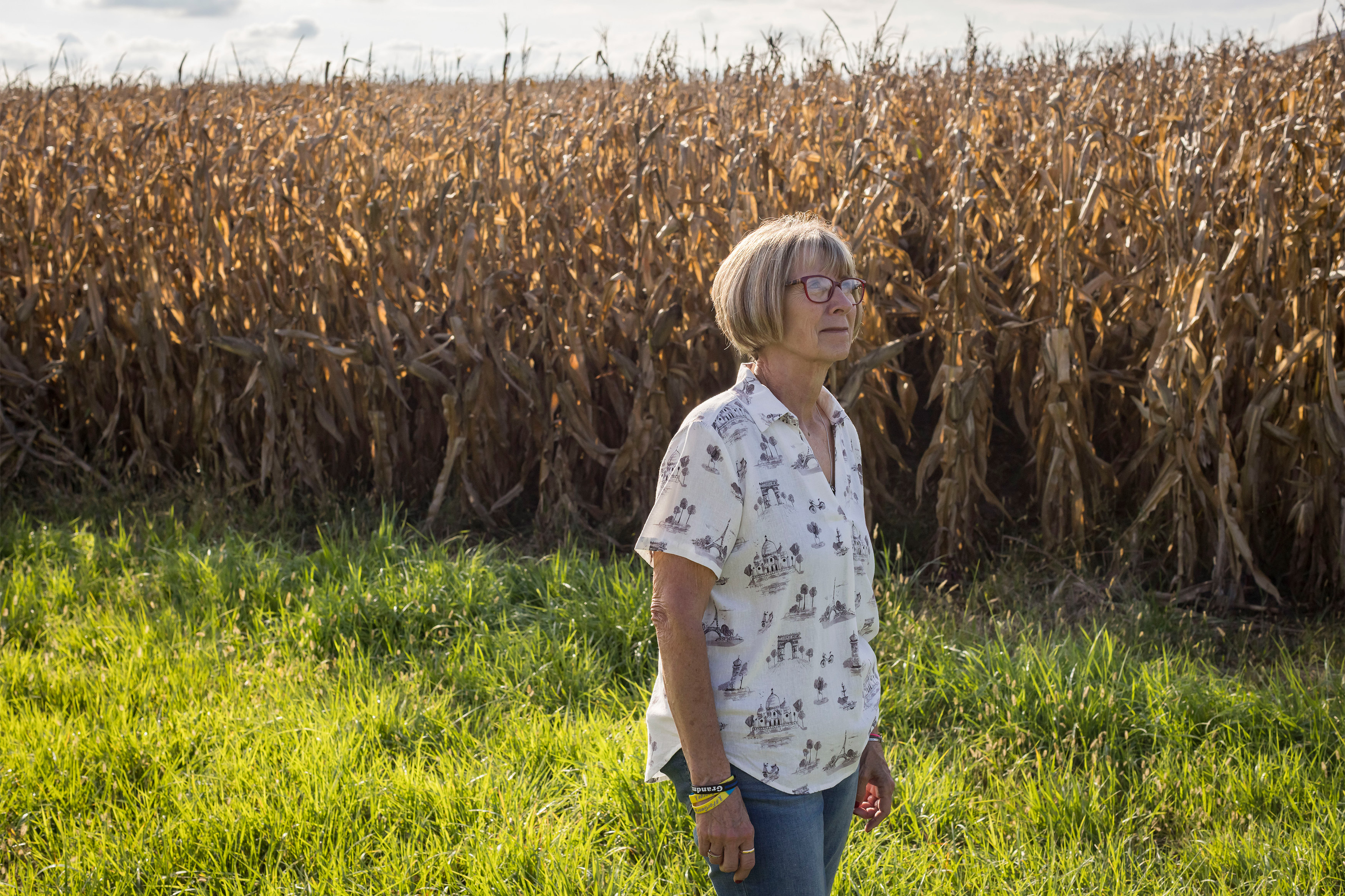 A photo of Donna Klocke standing in front of a cornfield in Iowa.