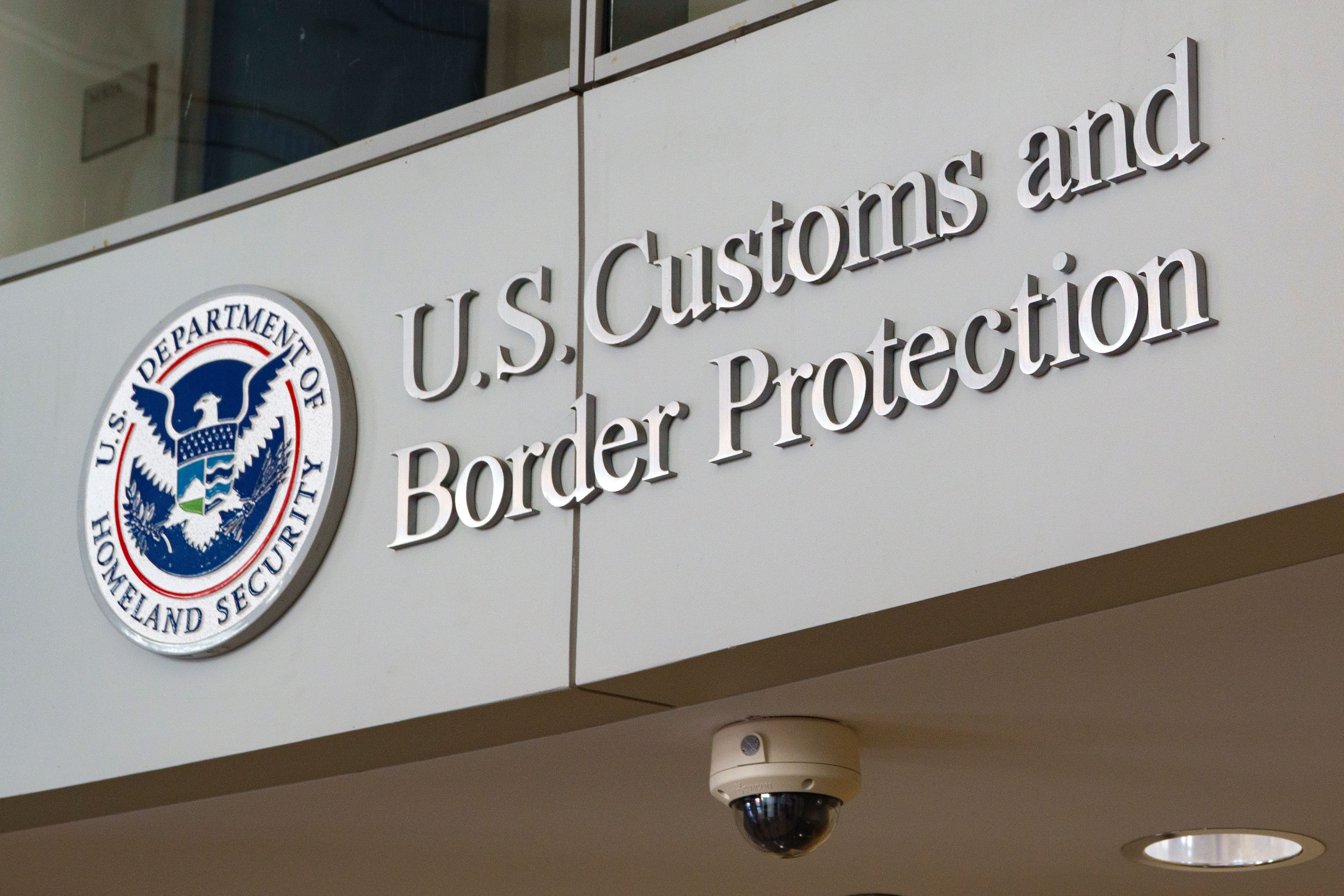 A sign on the side of a building has a seal and the words, "U.S. Customs and Border Protection," next to it.