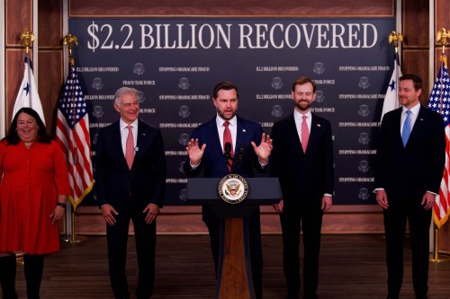 Vice President JD Vance (center) speaks alongside (left/right) Kimberly Brandt, Mehmet Oz, Andrew Ferguson Chris Klomp during a press conference. A large backdrop poster behind them says, "$2.2 BILLION RECOVERED."