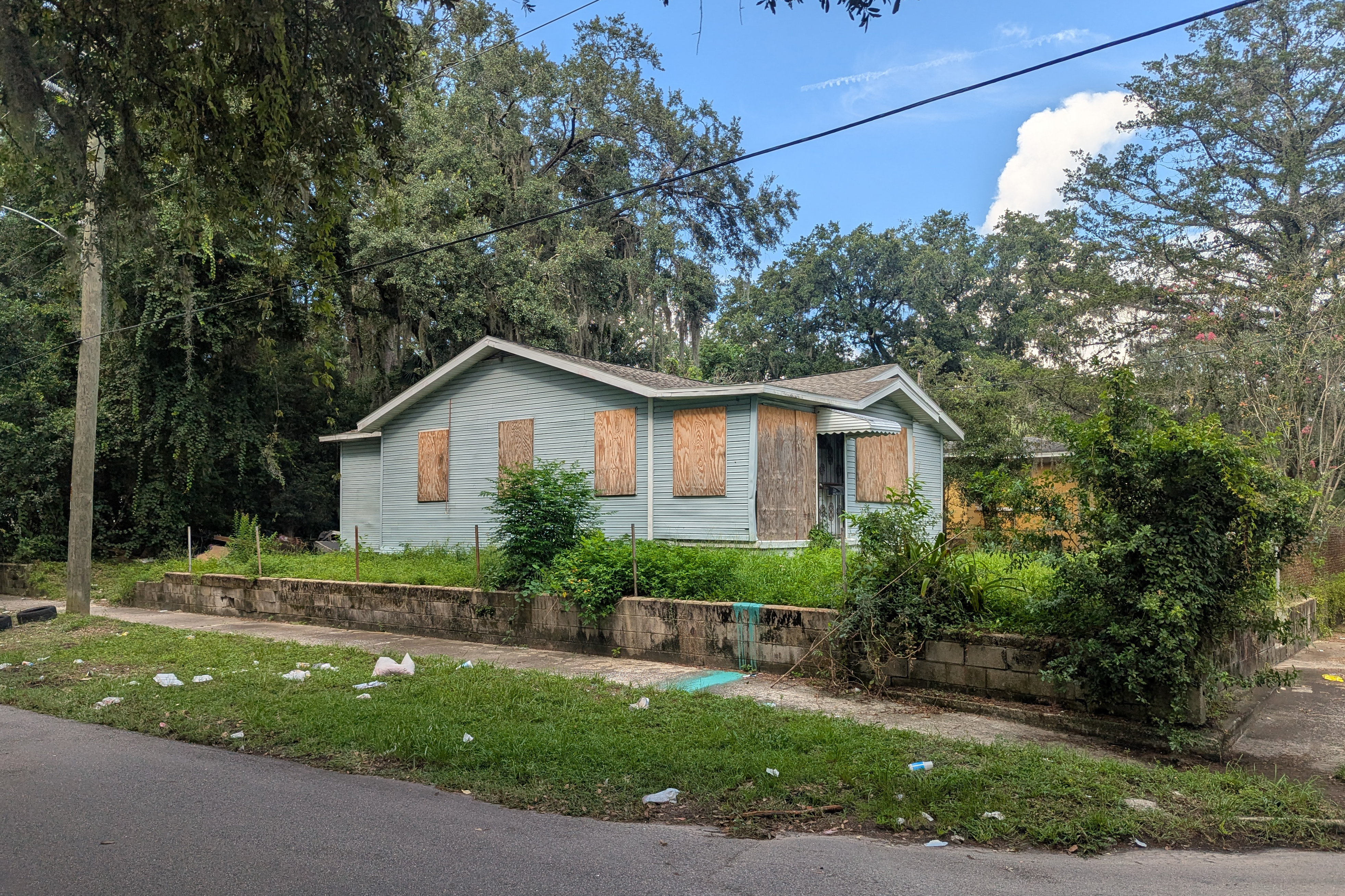 A photo of a blue house boarded up with panels of wood.
