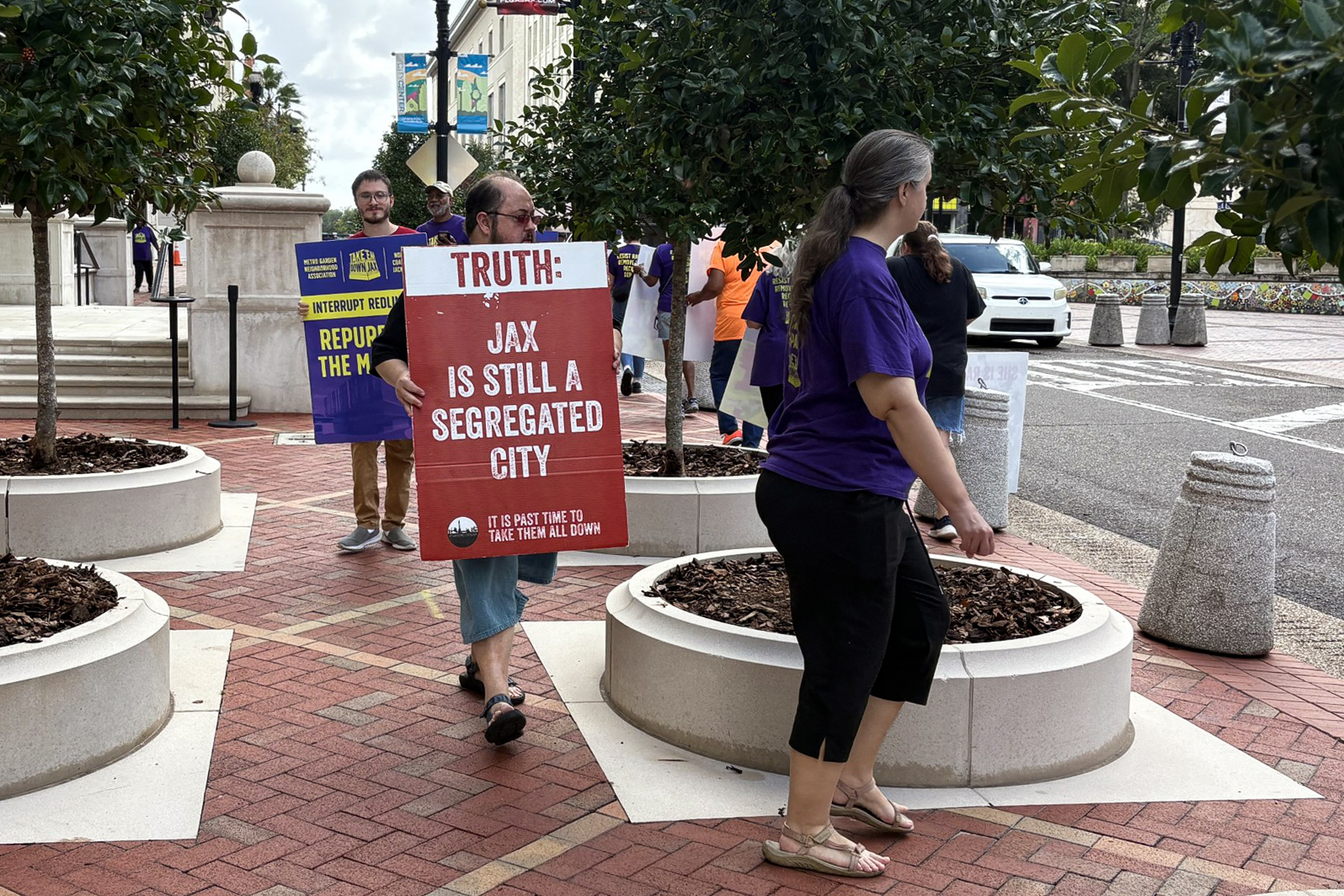 A group of protesters outside Jacksonville City Hall. One holds a sign that reads, "Truth: Jax is still a segregated city."