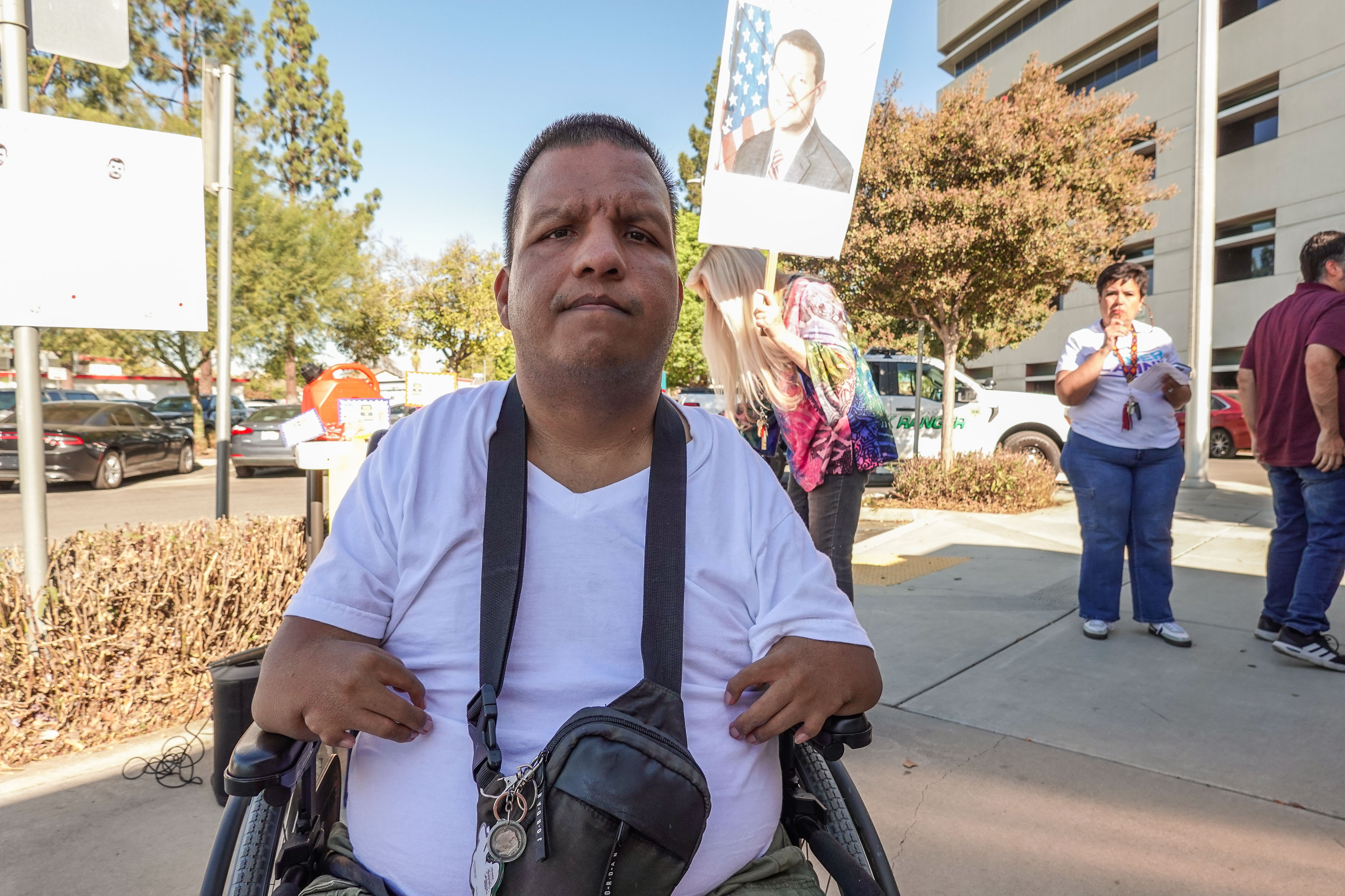 A portrait of a man with a physical disability sitting in a wheelchair with a serious expression.